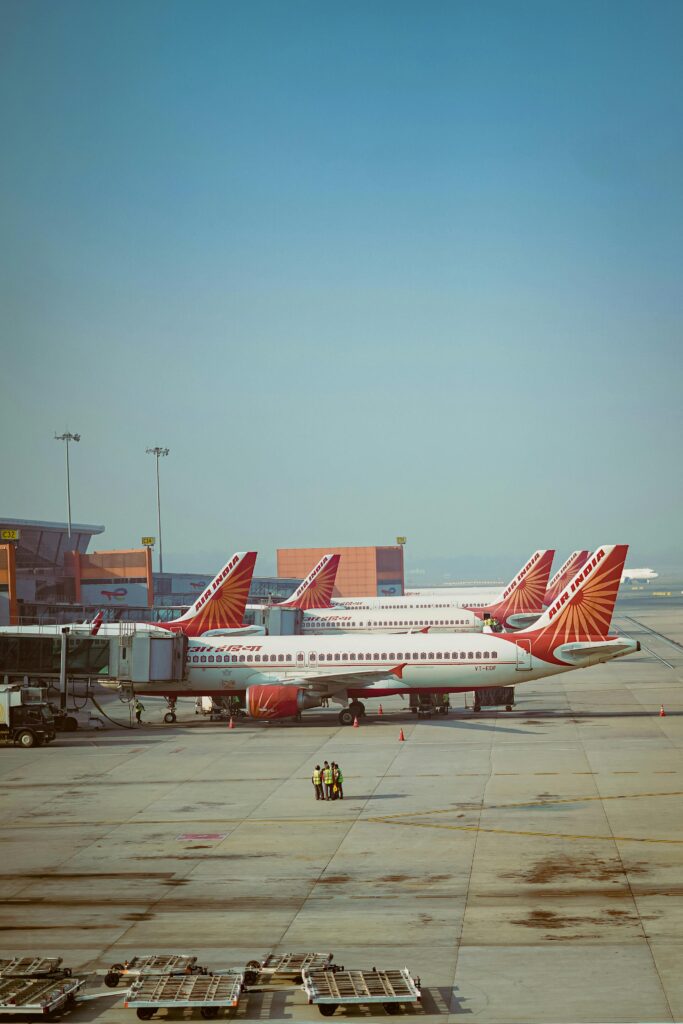 A fleet of Air India airplanes parked on the runway at an airport under clear blue skies.